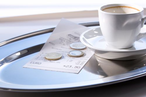 Foto: Trinkgeld auf Tablett mit leerer Kaffeetasse